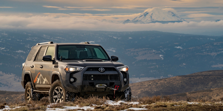 Toyota 4Runner todoterreno avanzando imponente entre una montaña con césped