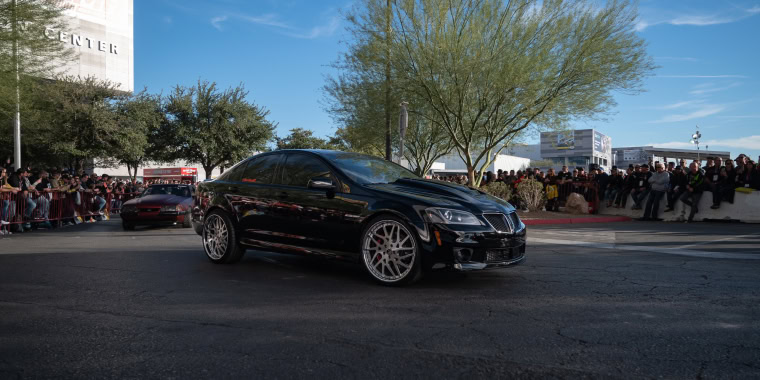 Pontiac G6 color negro avanzando en la calle en un evento de demostración de autos. 