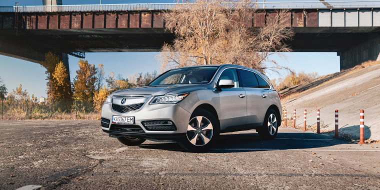 Acura MDX gris estacionado debajo de un puente.