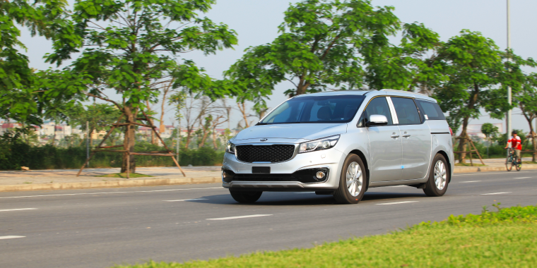 : Kia Sedona gris avanzando en la carretera frente a árboles – Freeway, seguro de auto barato para la Kia Sedona 